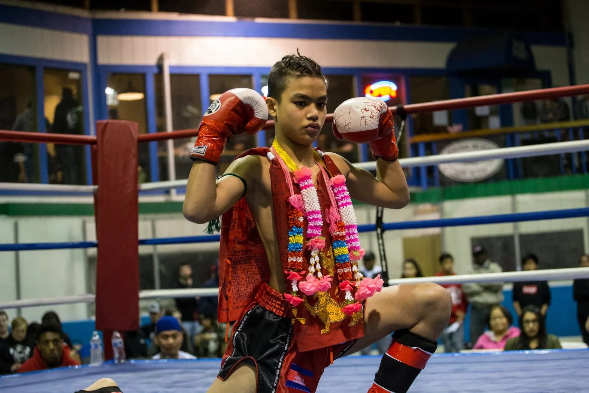 A young South Sound fighter in the ring with his guard up, wearing the traditional Kun Khmer garlands